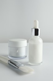 Bottle of chemical peel liquid, jar and brush on light background. Peeling procedure