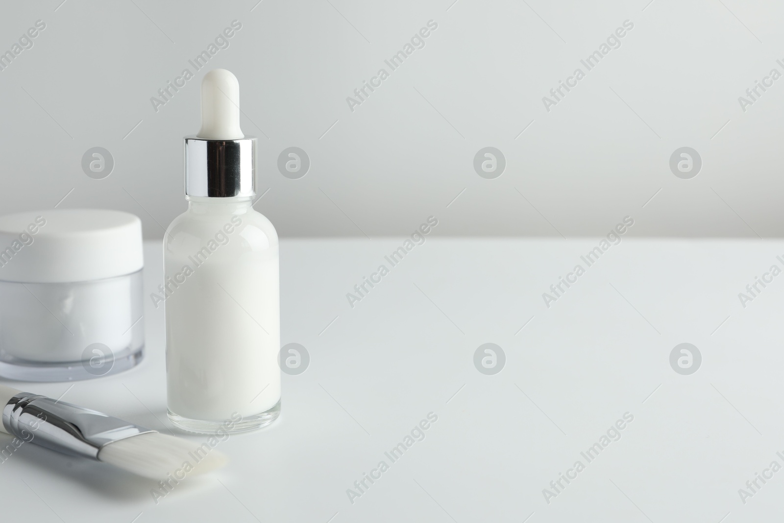 Photo of Bottle of chemical peel liquid, jar and brush on light background, space for text. Peeling procedure