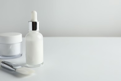 Bottle of chemical peel liquid, jar and brush on light background, space for text. Peeling procedure