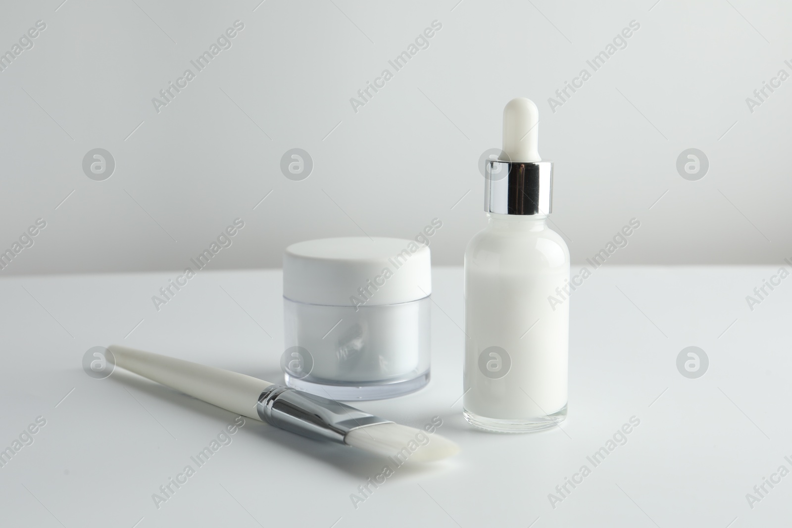 Photo of Bottle of chemical peel liquid, jar and brush on light background. Peeling procedure