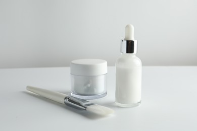 Bottle of chemical peel liquid, jar and brush on light background. Peeling procedure