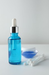 Photo of Bottle of chemical peel liquid, jar and cotton swabs on light background. Peeling procedure