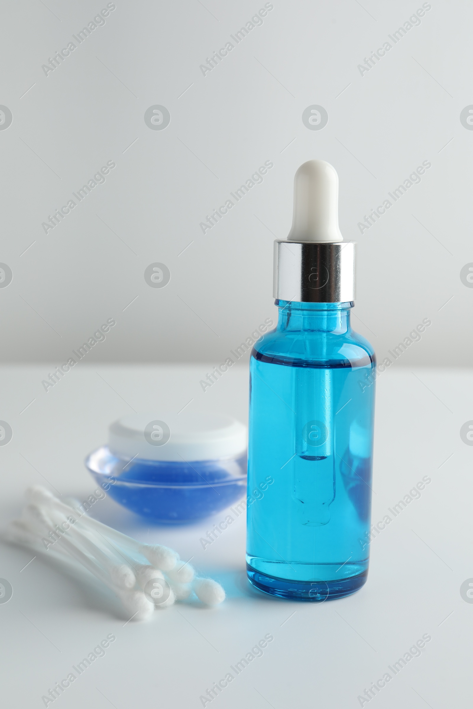 Photo of Bottle of chemical peel liquid, jar and cotton swabs on light background. Peeling procedure