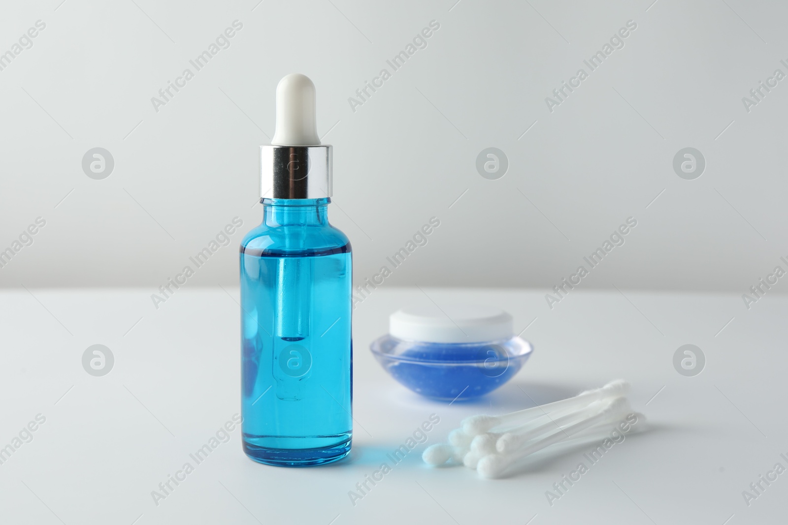 Photo of Bottle of chemical peel liquid, jar and cotton swabs on light background, space for text. Peeling procedure