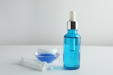 Photo of Bottle of chemical peel liquid, jar and cotton swabs on light background, space for text. Peeling procedure