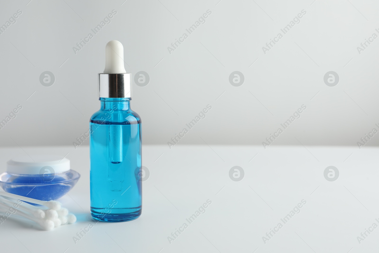 Photo of Bottle of chemical peel liquid, jar and cotton swabs on light background, space for text. Peeling procedure