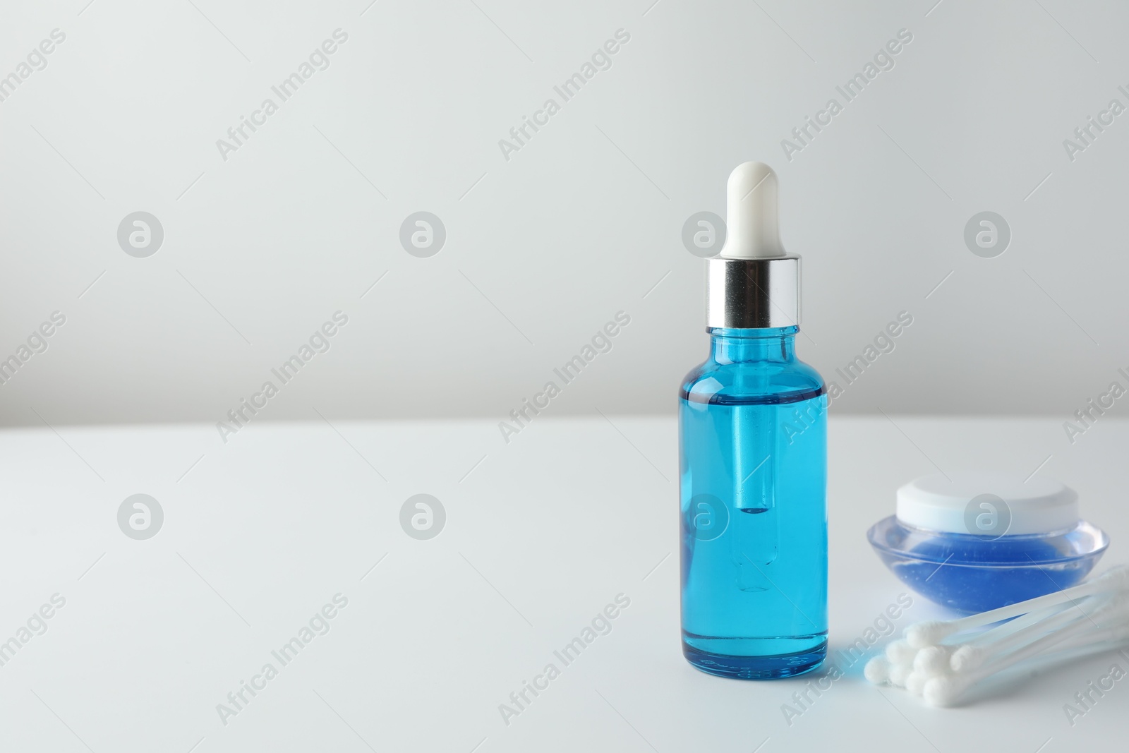 Photo of Bottle of chemical peel liquid, jar and cotton swabs on light background, space for text. Peeling procedure