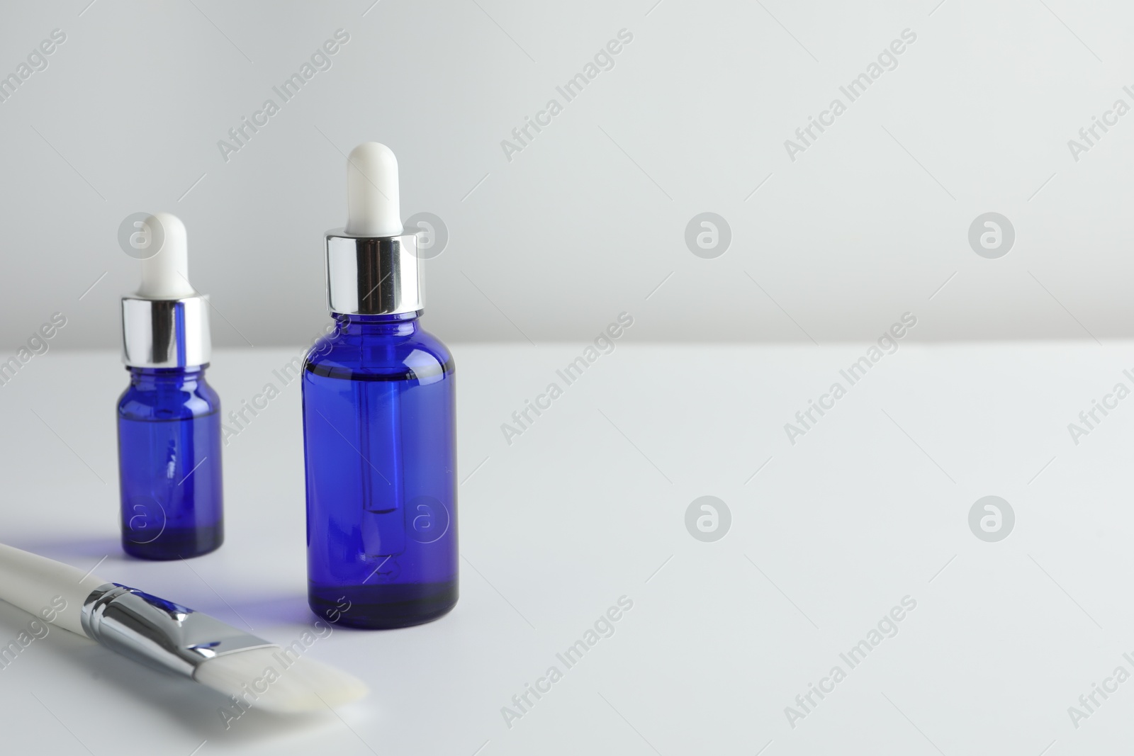 Photo of Bottles of chemical peel and brush on light background, space for text. Peeling procedure