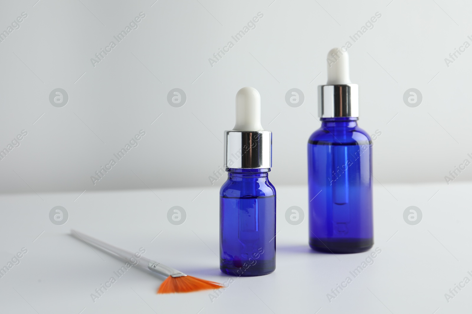 Photo of Bottles of chemical peel and brush on light background, space for text. Peeling procedure