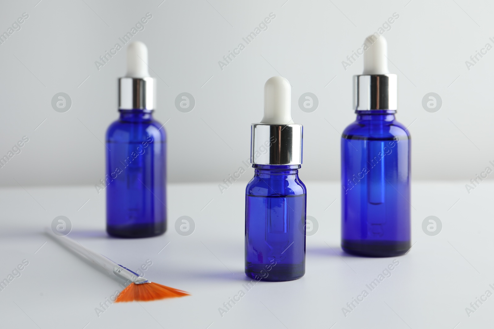 Photo of Bottles of chemical peel and brush on light background. Peeling procedure