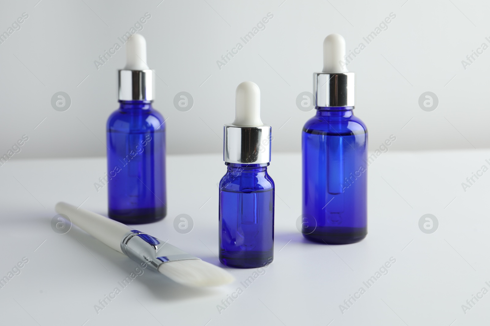 Photo of Bottles of chemical peel and brush on light background. Peeling procedure