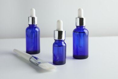 Bottles of chemical peel and brush on light background. Peeling procedure