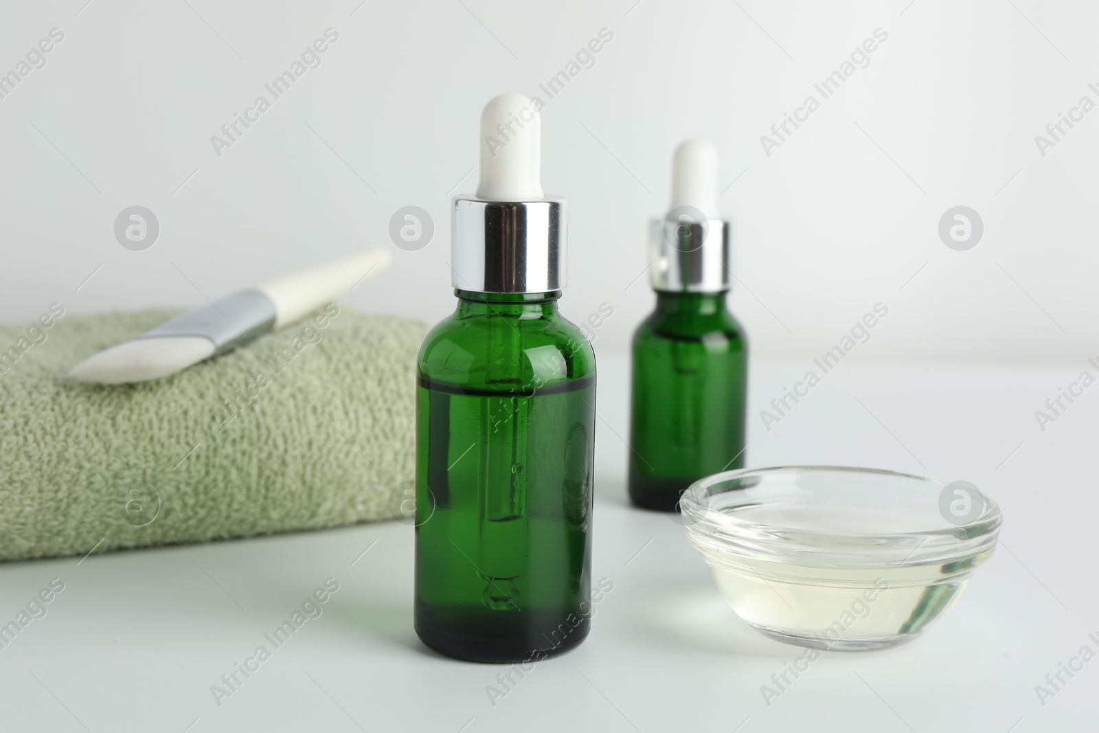 Photo of Bottles of chemical peel, bowl with liquid, towel and brush on light background, closeup. Peeling procedure