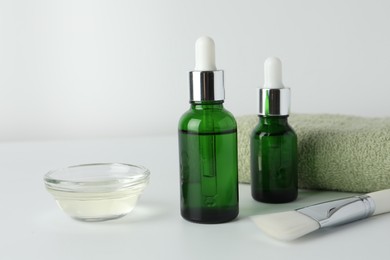 Bottles of chemical peel, bowl with liquid, towel and brush on light background, closeup. Peeling procedure