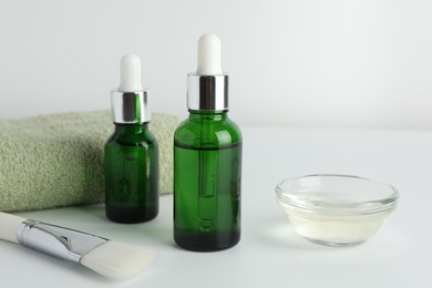 Photo of Bottles of chemical peel, bowl with liquid, towel and brush on light background, closeup. Peeling procedure