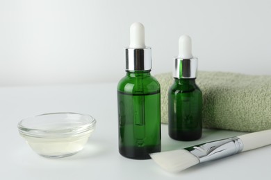 Bottles of chemical peel, bowl with liquid, towel and brush on light background, closeup. Peeling procedure