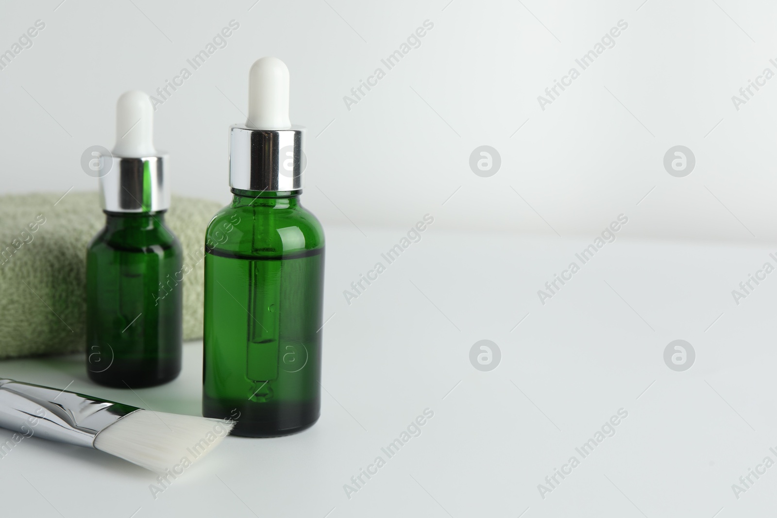 Photo of Peeling procedure. Bottles of chemical peel, towel and brush on light background, closeup. Space for text