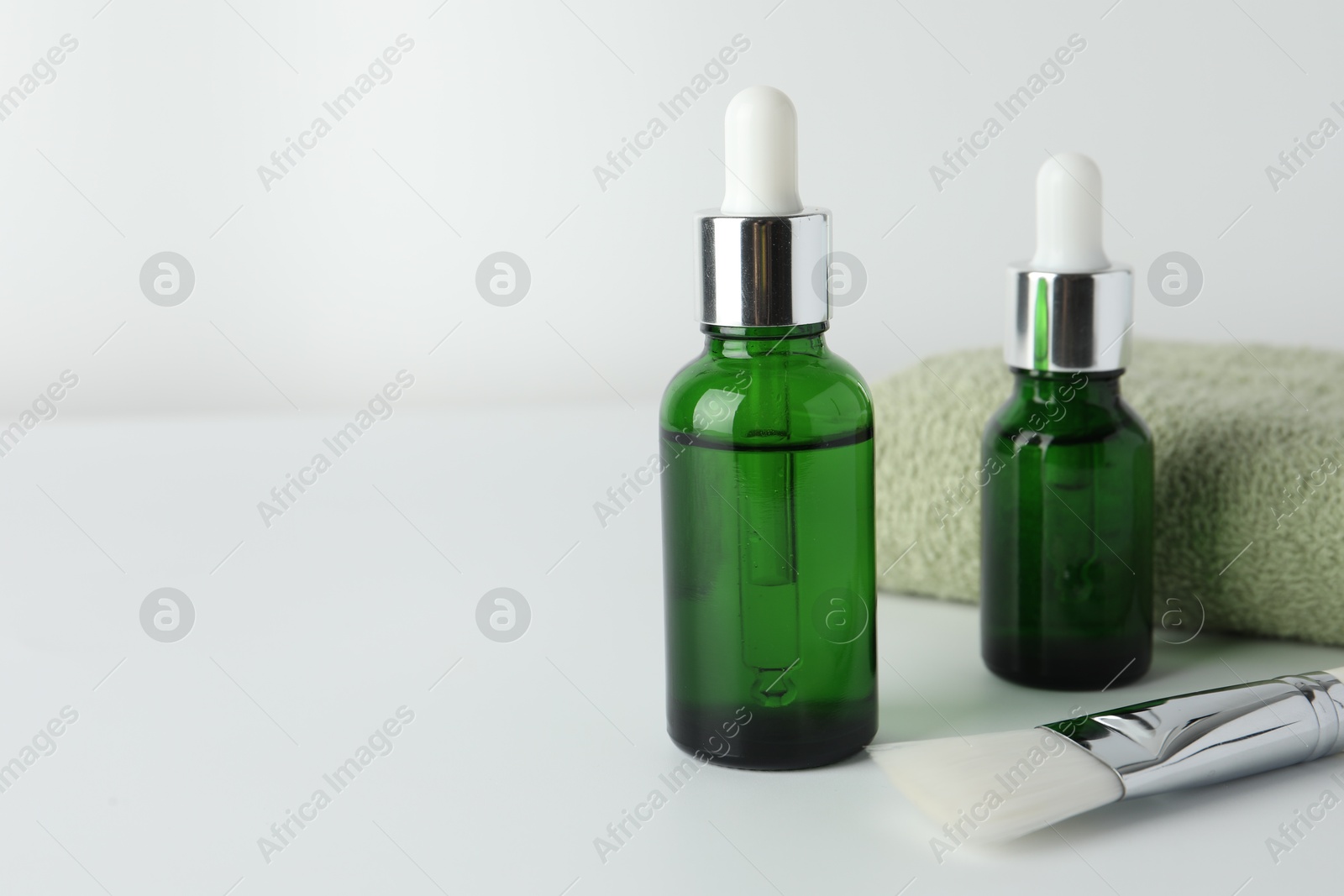 Photo of Peeling procedure. Bottles of chemical peel, towel and brush on light background, closeup. Space for text