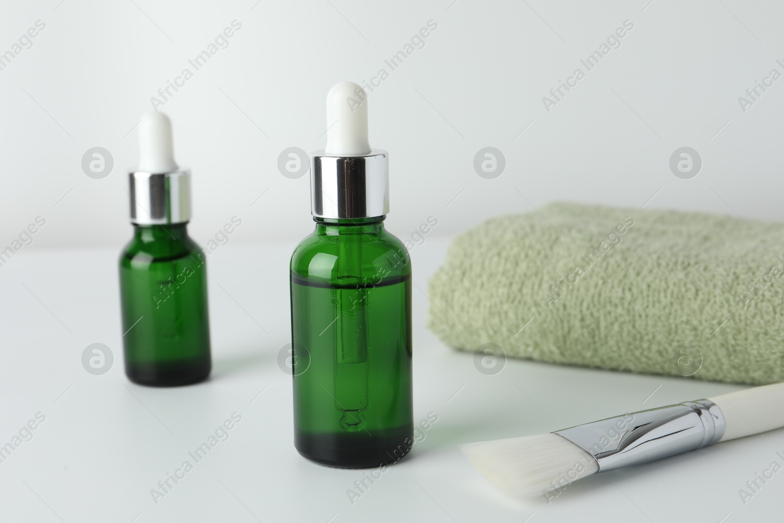 Photo of Bottles of chemical peel, towel and brush on light background, closeup. Peeling procedure