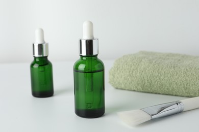 Bottles of chemical peel, towel and brush on light background, closeup. Peeling procedure