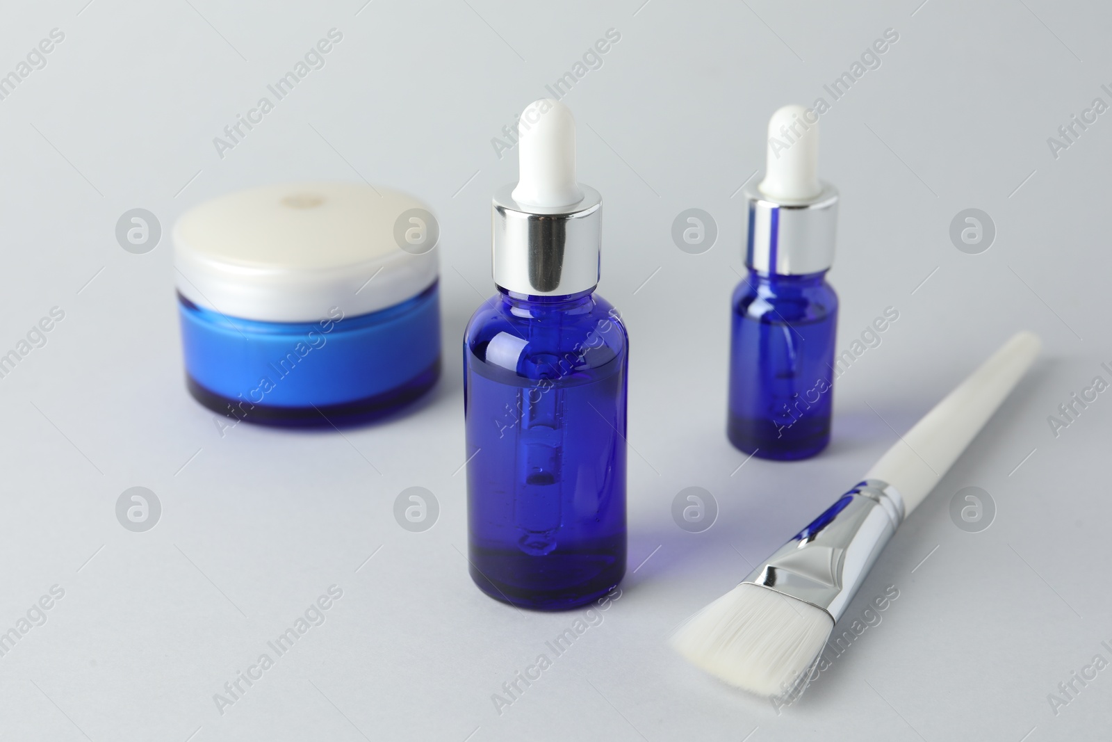 Photo of Bottles of chemical peel, jar and brush on light background. Peeling procedure