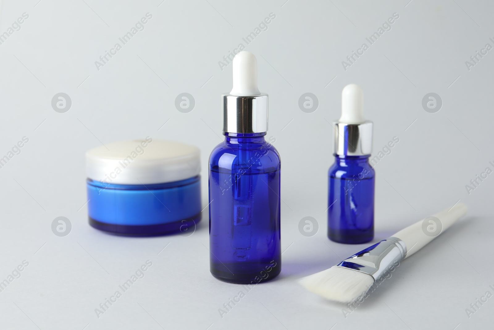 Photo of Bottles of chemical peel, jar and brush on light background. Peeling procedure