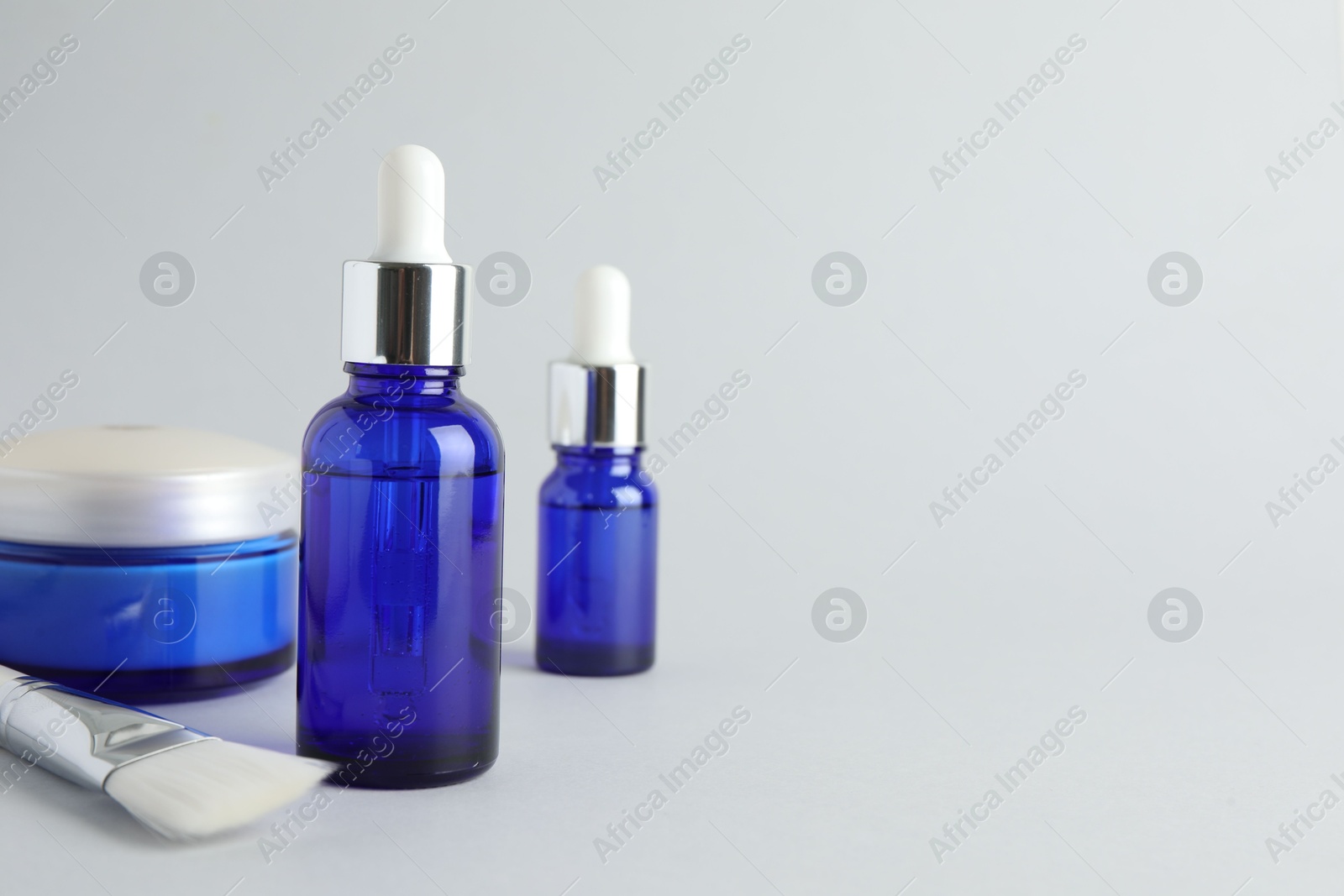 Photo of Bottles of chemical peel, jar and brush on light background, space for text. Peeling procedure