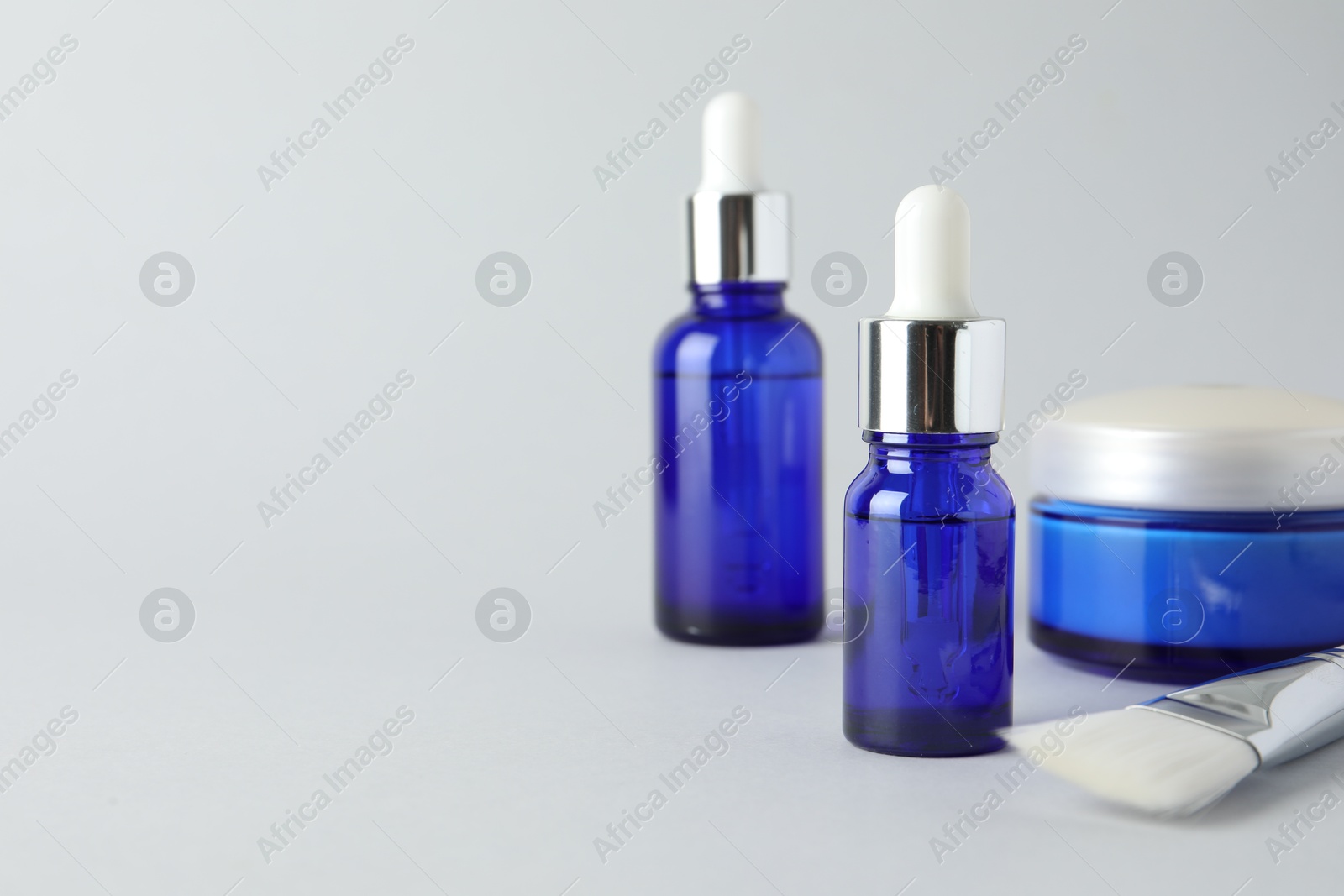 Photo of Bottles of chemical peel, jar and brush on light background, space for text. Peeling procedure