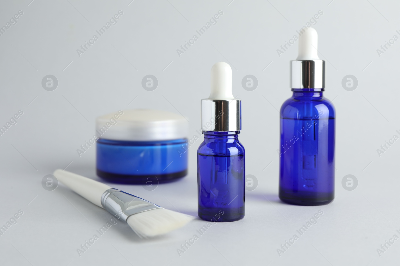 Photo of Bottles of chemical peel, jar and brush on light background. Peeling procedure