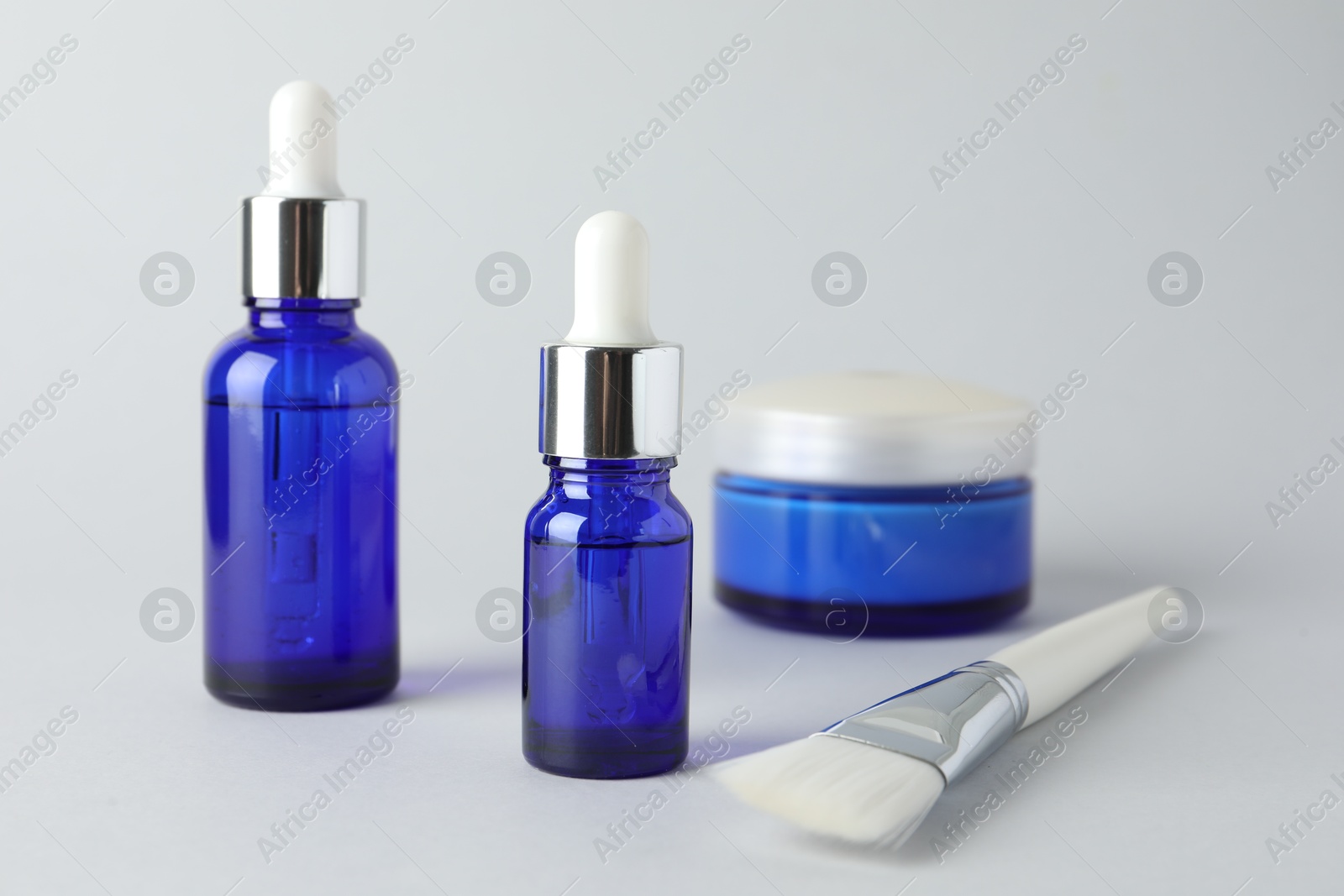 Photo of Bottles of chemical peel, jar and brush on light background, closeup. Peeling procedure