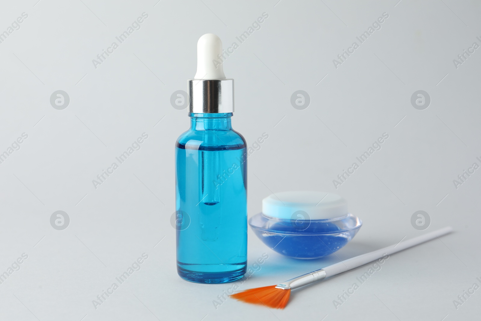 Photo of Bottle of chemical peel liquid, jar and brush on light background. Peeling procedure