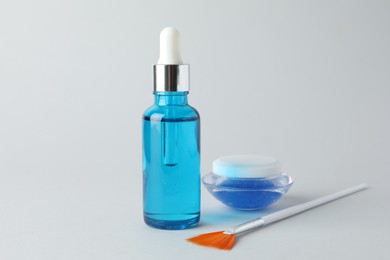 Bottle of chemical peel liquid, jar and brush on light background. Peeling procedure