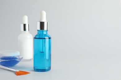 Photo of Bottles of chemical peel, jar and brush on light background, space for text. Peeling procedure