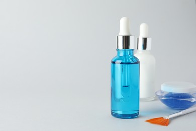 Photo of Bottles of chemical peel, jar and brush on light background, space for text. Peeling procedure