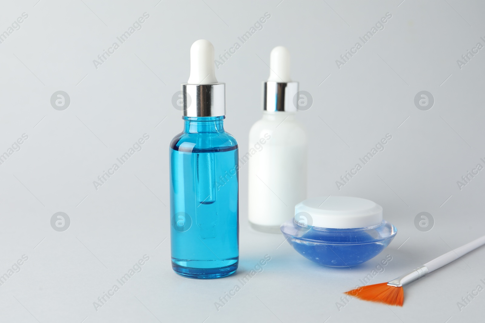 Photo of Bottles of chemical peel, jar and brush on light background. Peeling procedure