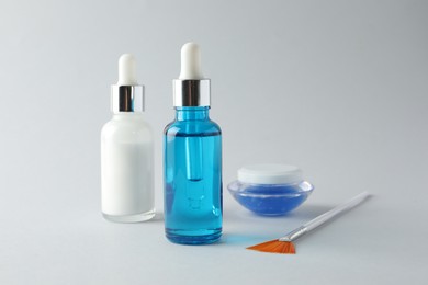 Photo of Bottles of chemical peel, jar and brush on light background. Peeling procedure