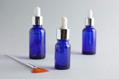 Photo of Bottles of chemical peel and brush on light background, closeup. Peeling procedure