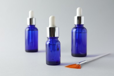 Photo of Bottles of chemical peel and brush on light background, closeup. Peeling procedure