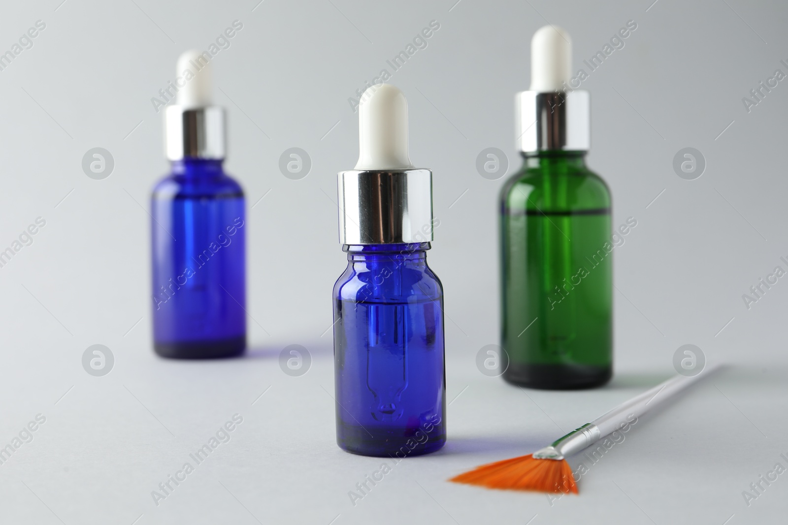 Photo of Bottles of chemical peel and brush on light background, closeup. Peeling procedure