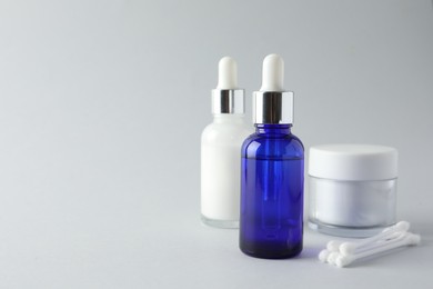 Photo of Bottles of chemical peel, jar and cotton swabs on light background, space for text. Peeling procedure