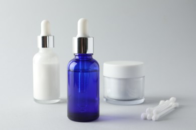 Photo of Bottles of chemical peel, jar and cotton swabs on light background, closeup. Peeling procedure