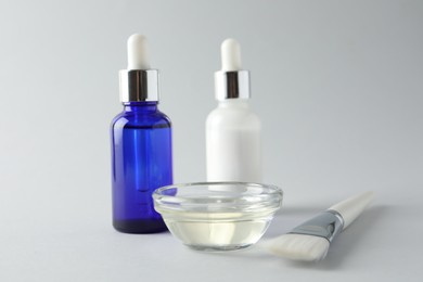 Bottles of chemical peel, bowl with liquid and brush on light background, closeup. Peeling procedure