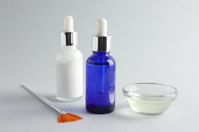 Bottles of chemical peel, bowl with liquid and brush on light background, closeup. Peeling procedure