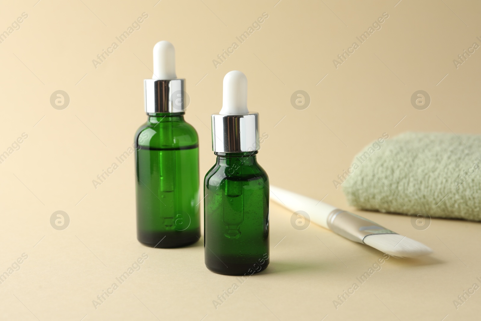 Photo of Bottles of chemical peel, towel and brush on beige background. Peeling procedure