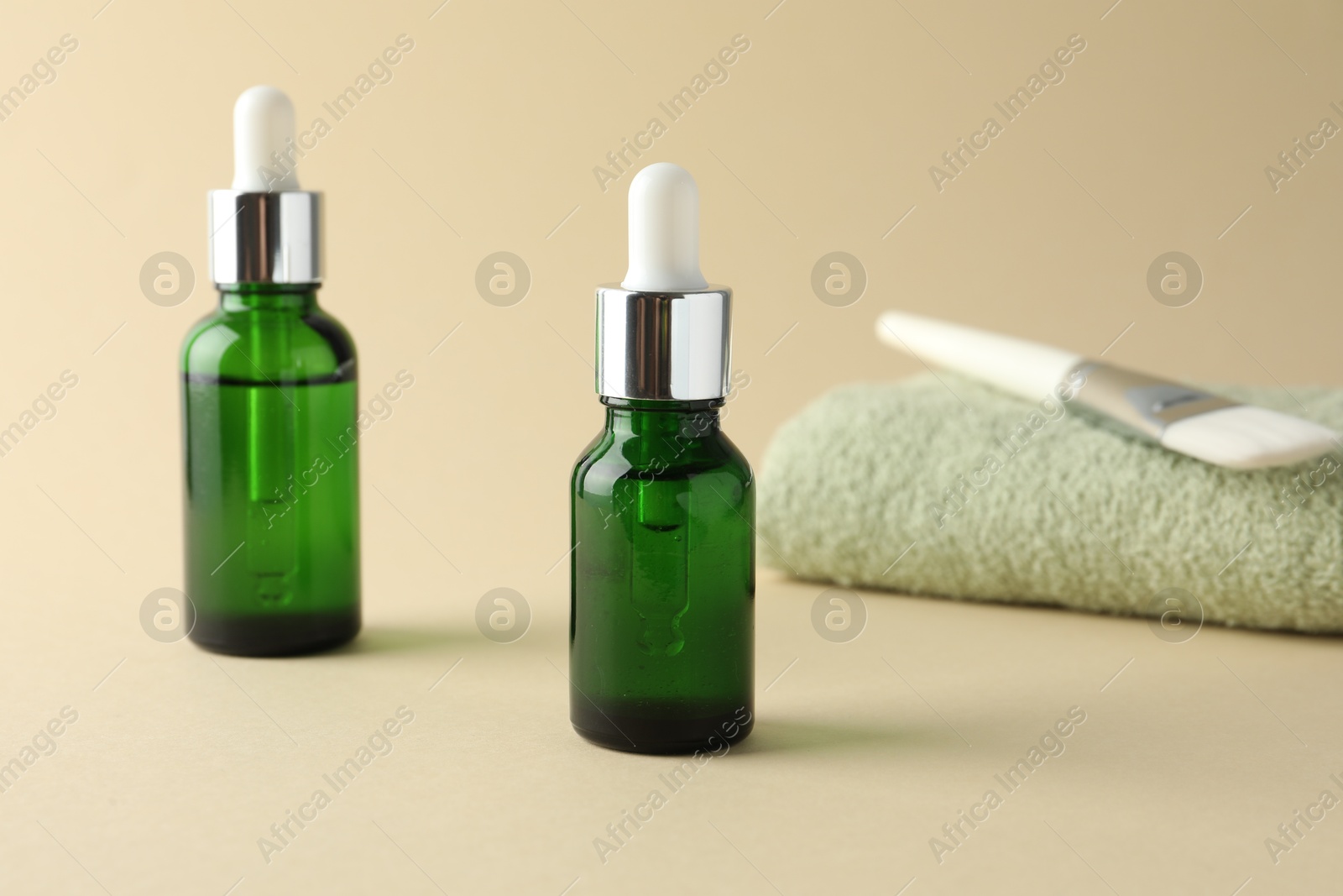 Photo of Bottles of chemical peel, towel and brush on beige background. Peeling procedure