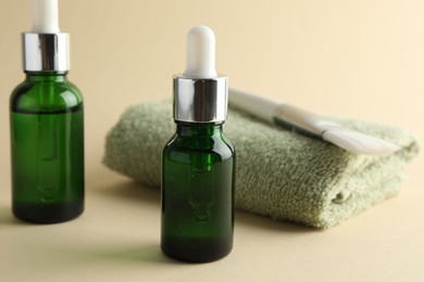 Photo of Bottles of chemical peel, towel and brush on beige background, closeup. Peeling procedure