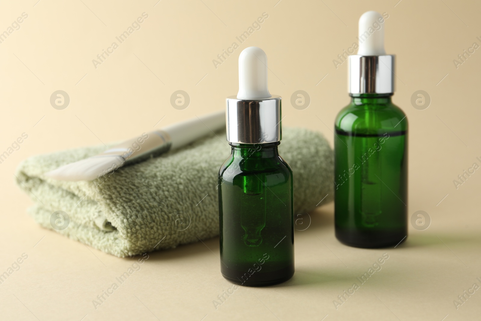 Photo of Bottles of chemical peel, towel and brush on beige background, closeup. Peeling procedure