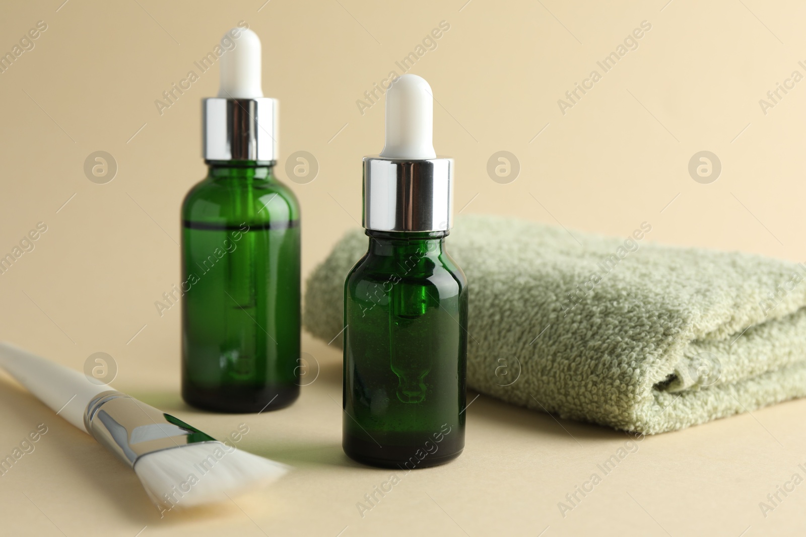 Photo of Bottles of chemical peel, towel and brush on beige background, closeup. Peeling procedure