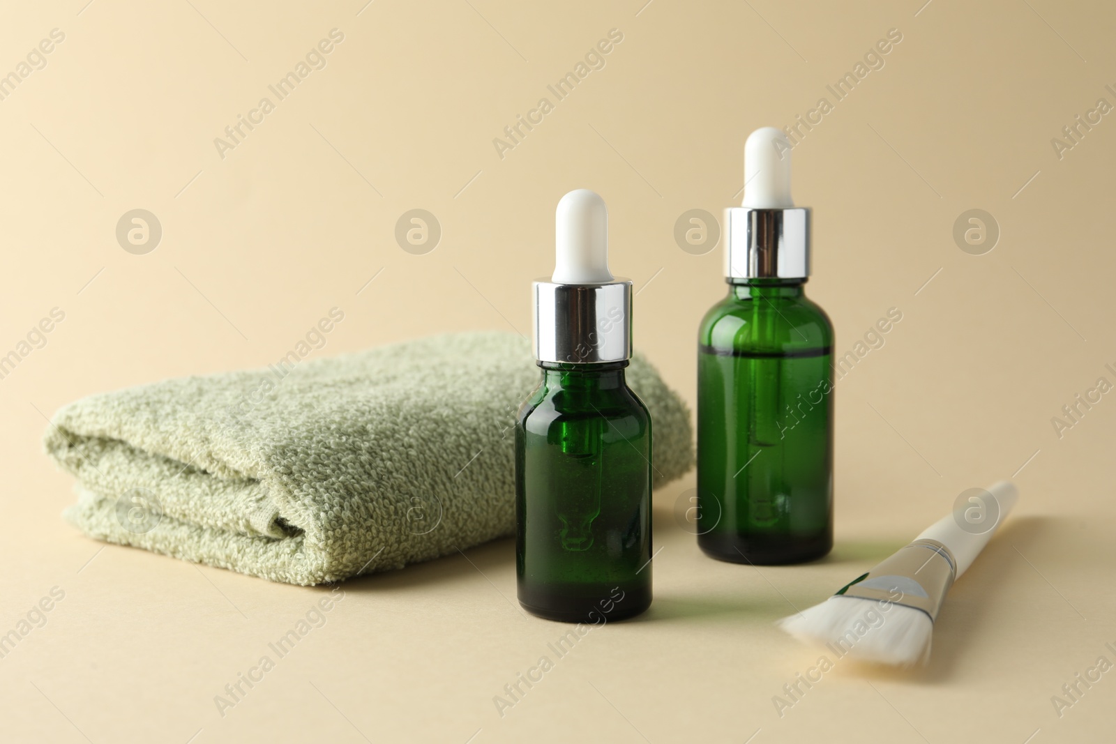 Photo of Bottles of chemical peel, towel and brush on beige background. Peeling procedure