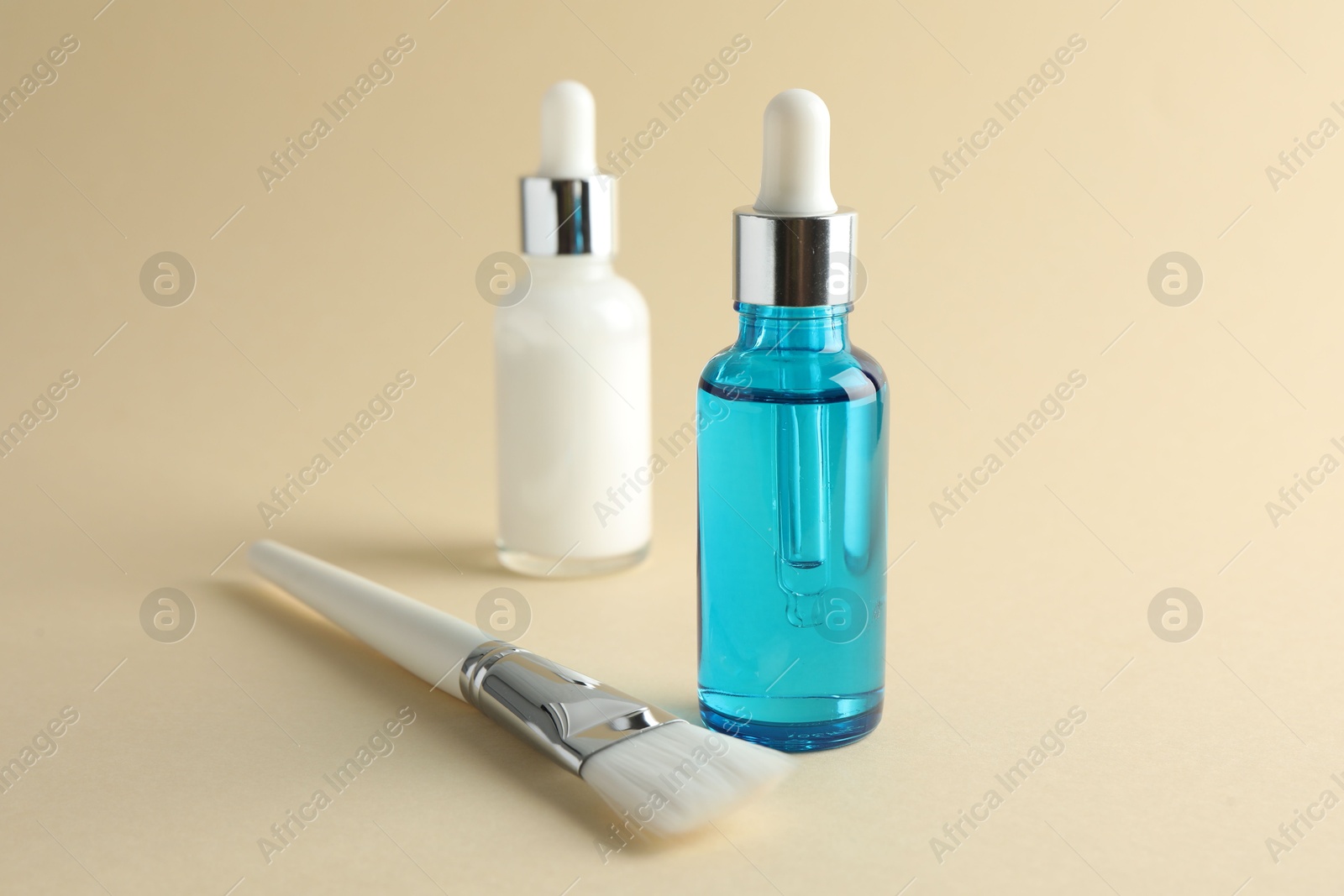 Photo of Bottles of chemical peel and brush on beige background, closeup. Peeling procedure